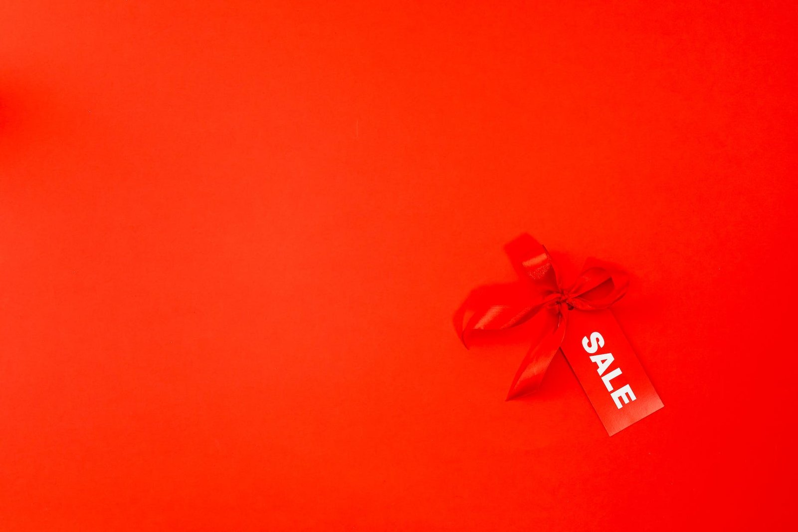 a red ribbon and sale tag on red background
