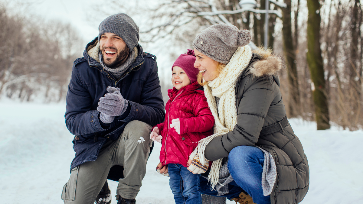 A family of three smiling and enjoying one of best winter vacations in the us.